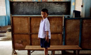 An Indian school boy stands on a class r